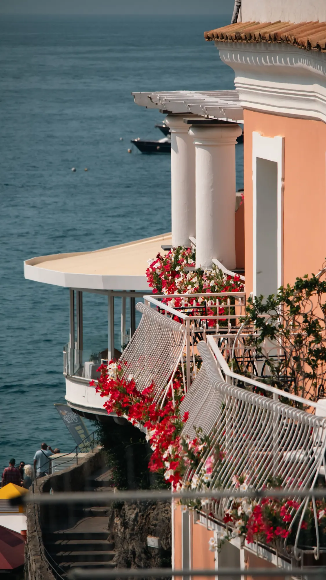Balcony of a coastal villa above the sea, framed by bougainvillea