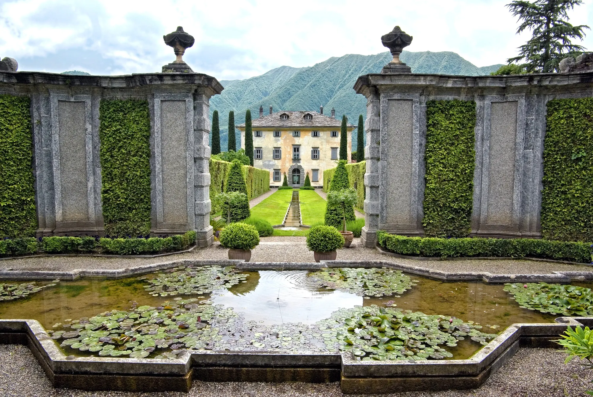 Formal garden with a lily pond leading to a lakeside villa