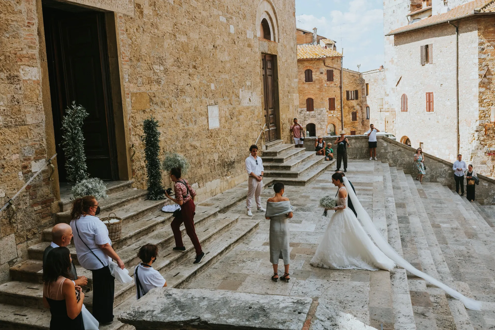 Bride on the stone steps of a medieval hill town, guests looking on